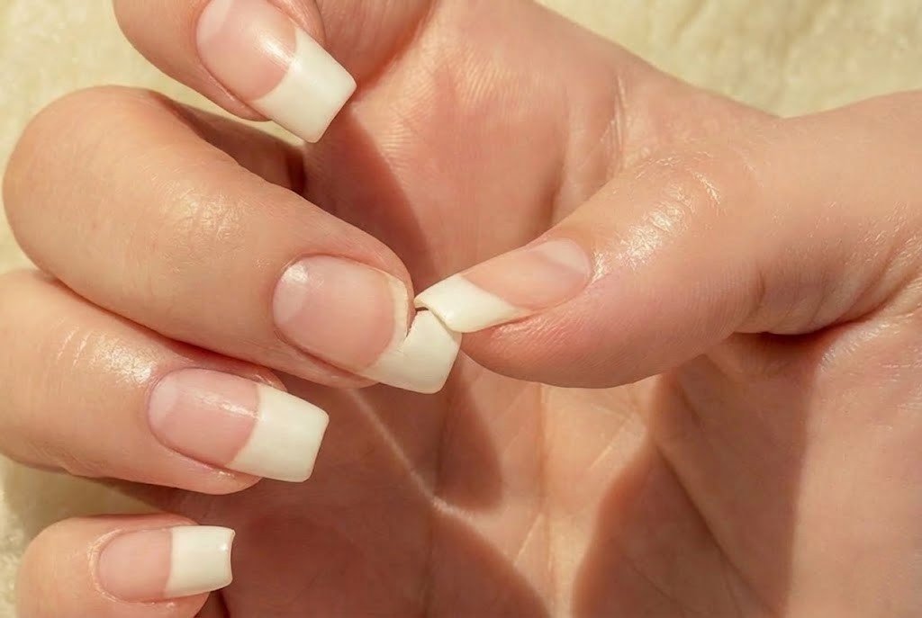 broken nail being pulled apart showing damage that slows nail growth and sets back progress