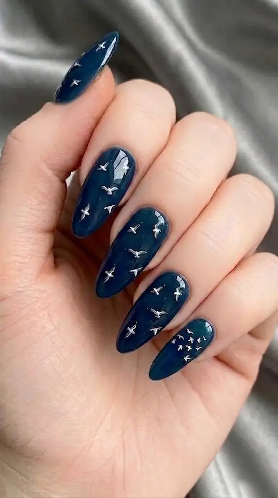 moody teal beach nail designs with metallic silver birds in flight on almond nails