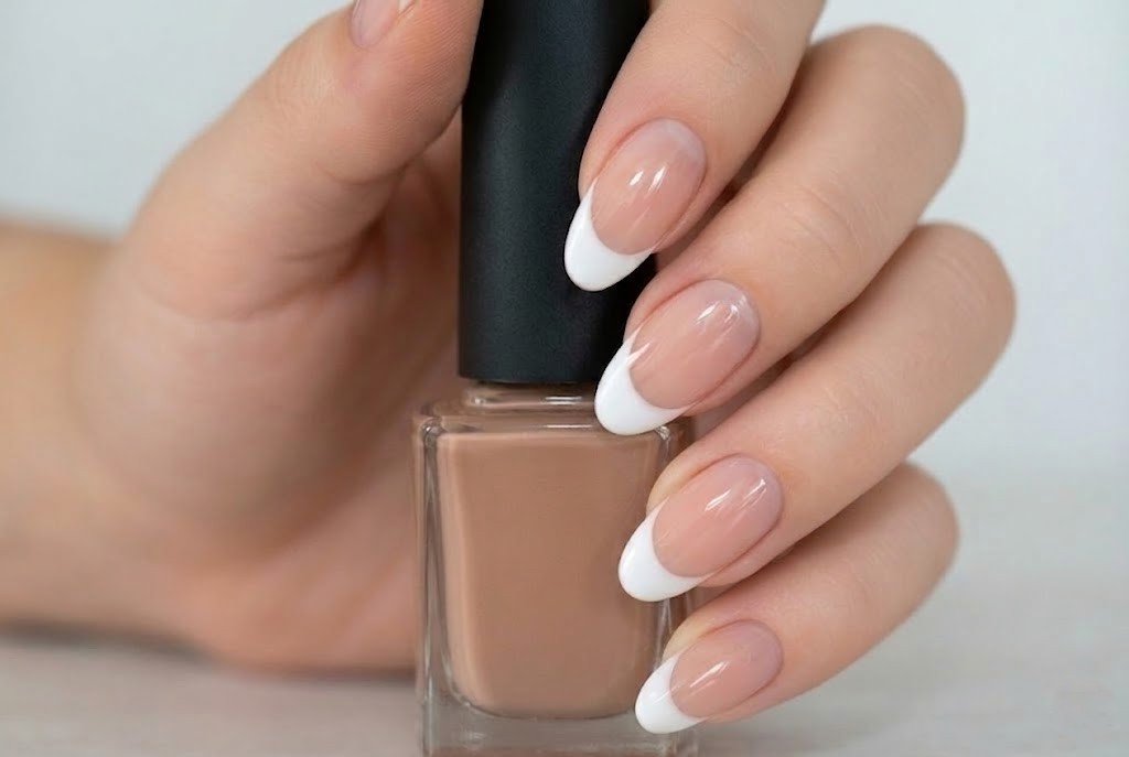 long french tip nails holding nude nail polish bottle showing healthy nail growth results