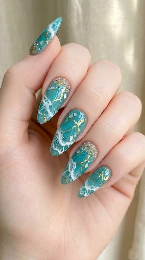 deep teal marble beach nails with gold foil and iridescent shell on long almond nails