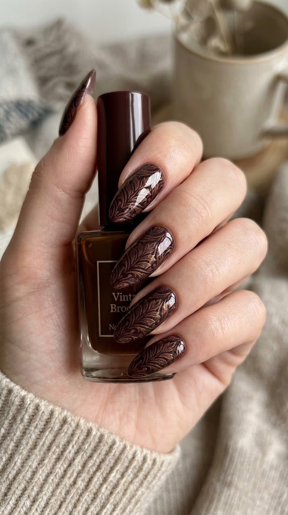 Long almond nails featuring dark burgundy and metallic bronze vintage brocade textile print