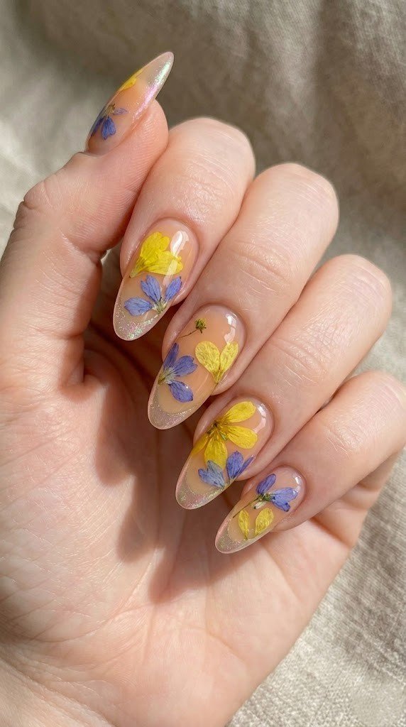 Clear jelly nails with pressed yellow and periwinkle wildflowers and iridescent French tip shimmer