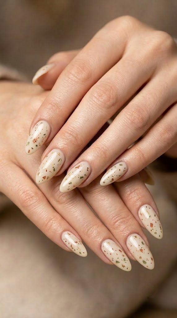Terracotta, olive, and gold quartz flecks scatter across cream nails, classy September nail designs done right.